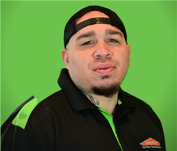 A male SERVPRO employee smiles infront of a green background.
