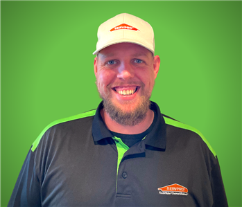 A male SERVPRO employee smiles in front of a green background.